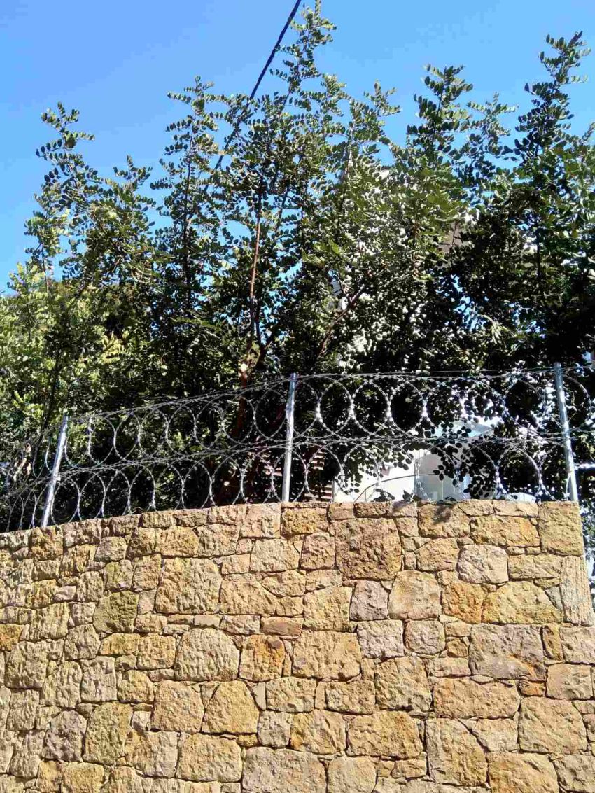 Περίφραξη με λεπιδοφόρο κονσερτίνα σε πέτρινο τοίχο
