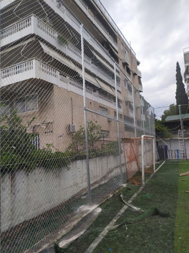 Υψηλή περίφραξη από γαλβανισμένο σύρμα πλέγματος, σχεδιασμένη για αντοχή και ασφάλεια σε γήπεδα ποδοσφαίρου