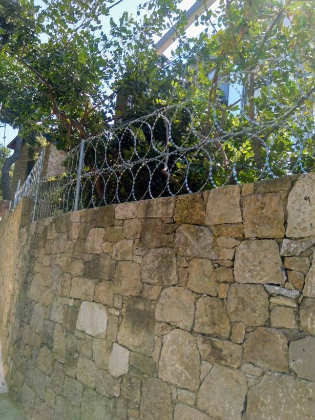 Περίφραξη με λεπιδοφόρο κονσερτίνα σε πέτρινο τοίχο
