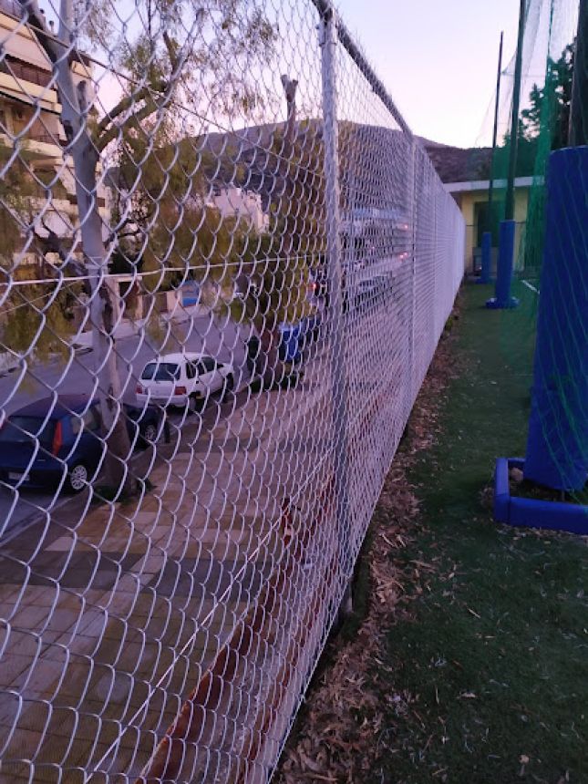 Περίφραξη με γαλβανισμένο πλέγμα υψηλής αντοχής, εγκατεστημένη κατά μήκος του γηπέδου για διαχωρισμό και ασφάλεια. Στηρίζεται σε μεταλλικούς στύλους