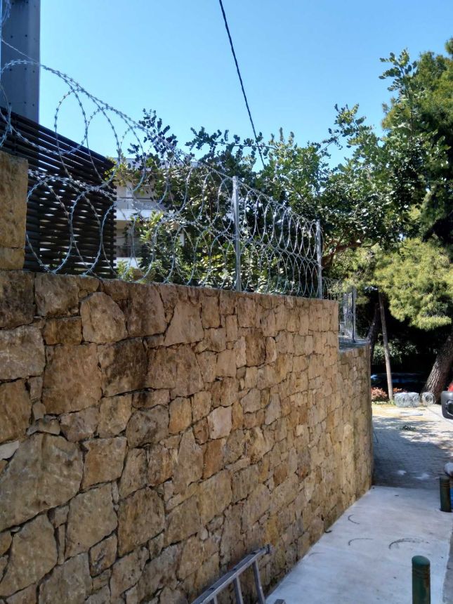 Περίφραξη με λεπιδοφόρο κονσερτίνα σε πέτρινο τοίχο