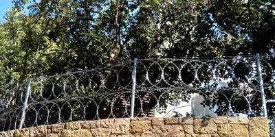Περίφραξη με λεπιδοφόρο κονσερτίνα σε πέτρινο τοίχο