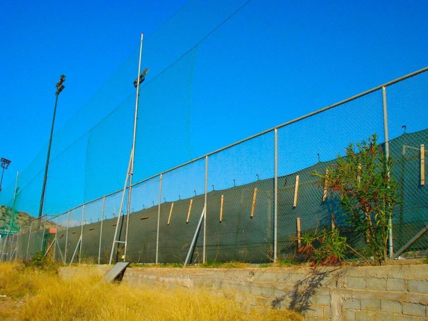Περίφραξη γηπέδου με μεταλλικούς στύλους, συρματόπλεγμα, τσιμεντένια βάση και ανθεκτικά υλικά κατάλληλα για αθλητικές χρήσεις.